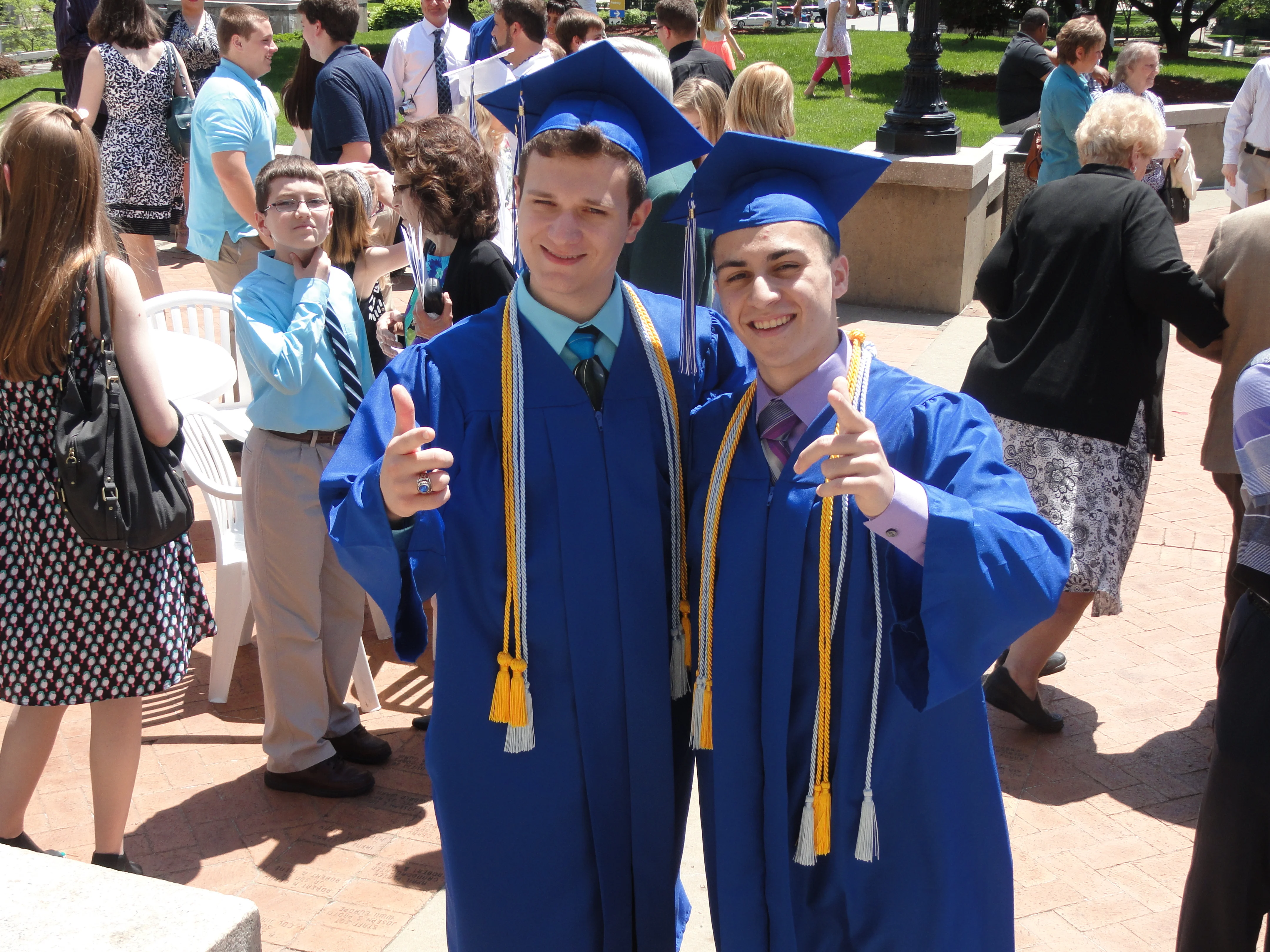 Mark and Zach Mell in blue caps and gowns with honor cords outside Soldiers and Sailors Memorial Hall after graduation.