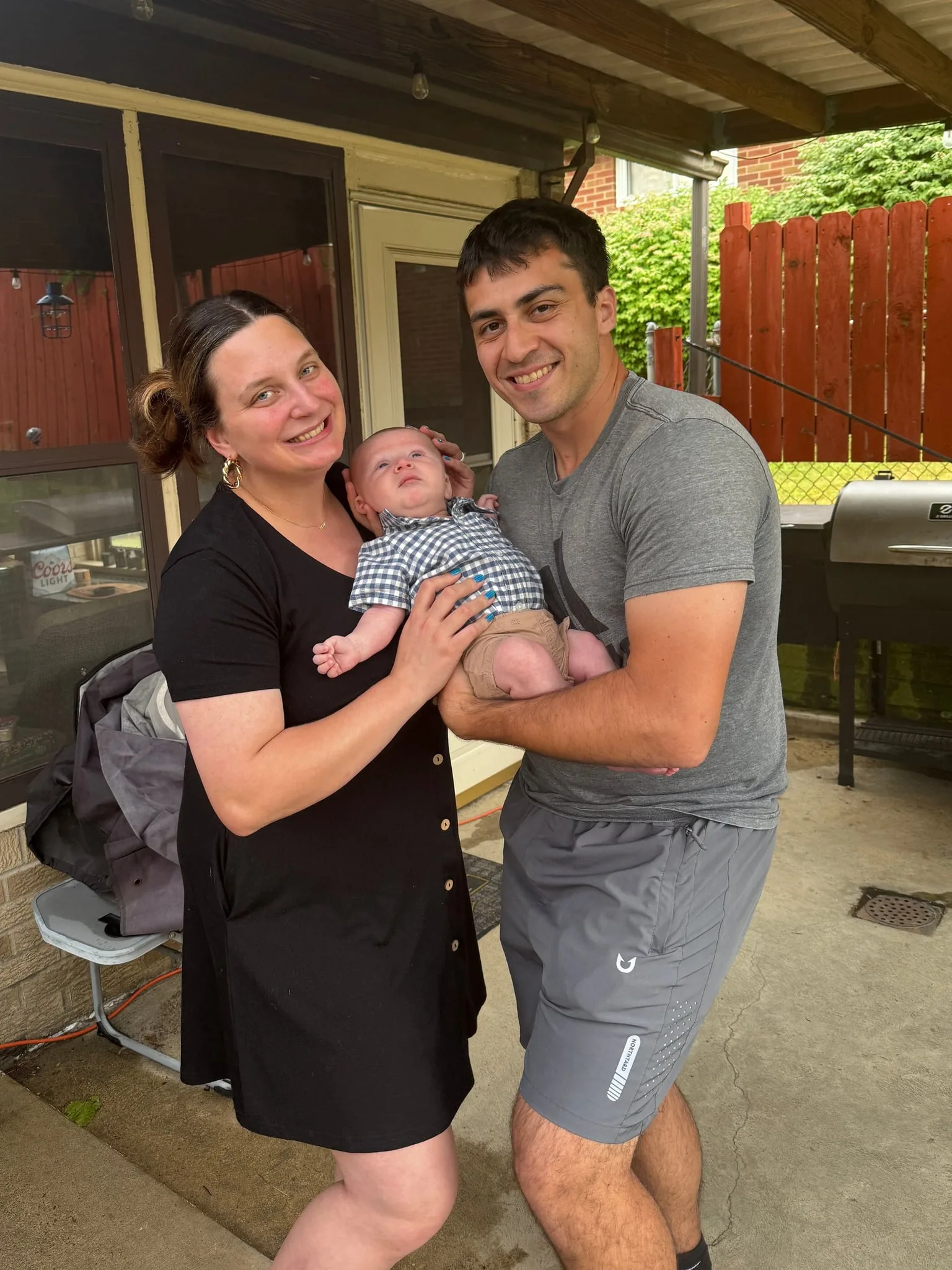 Mark, Amanda, and baby Nolan together on the back patio by the grill