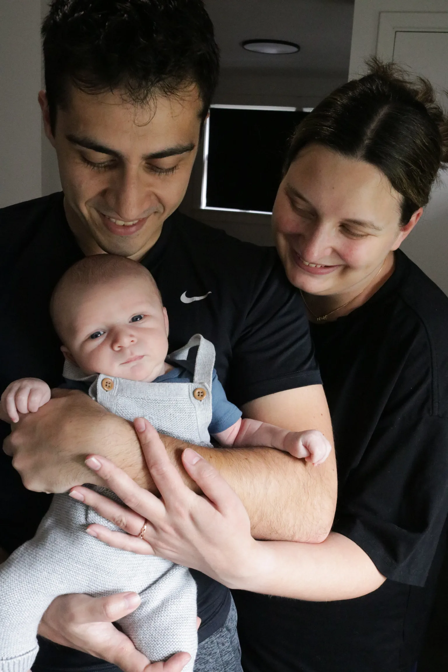 Mark and Amanda holding baby Nolan close, both looking down at him smiling